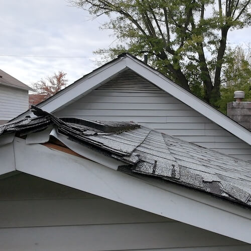 shingle roof with damage from a fallen tree